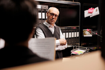 Senior police officer explaining confidential information to private detective, working overhours...