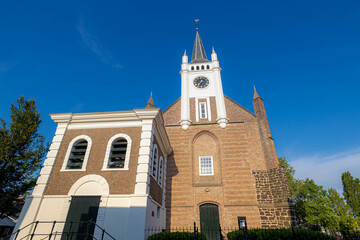 White clock tower of Reformed Church (Dutch: Gereformeerde or Hervormde kerk) The oldest building in the town centre, Bouwstraat, Ommen, A city in the Dutch province of Overijssel, Netherlands.