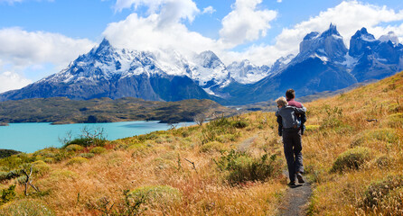 family of two, father and son, enjoying hiking and active travel in torres del paine national park in patagonia, chile, view of cuernos del paine and pehoe lake