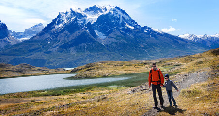 family of two, father and son, enjoying hiking and active travel in torres del paine national park in patagonia, chile, view of cuernos del paine