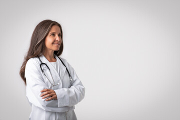 Professional medical worker. Portrait of happy senior woman doctor in white coat standing with folded arms, free space