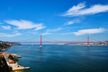 View of 25 de Abril Bridge famous tourist landmark of Lisbon connecting Lisboa to Almada on Setubal Peninsula over Tagus river with boats yachts and vessels. Lisbon, Portugal