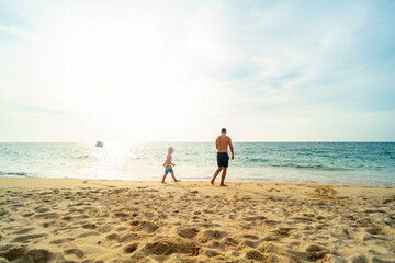 Father and son walking on summer beach. Dad and child having fun outdoors. Family travel, vacation