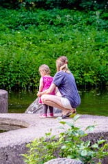 Fototapeta premium A woman and her daughter are standing on the lake in summer 