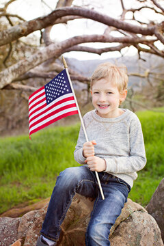 smiling caucasian boy holding american flag celebrating 4th of july, independence day