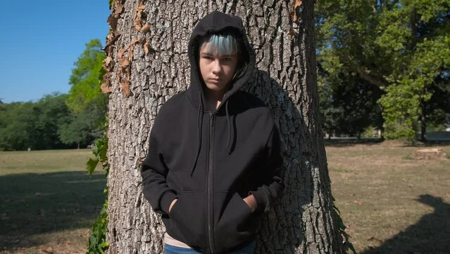Teen with depression by tree in wood. A teen girl in depression stand by the old tree in the sunny forest in the day light.