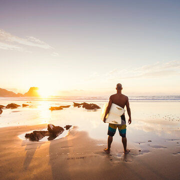 Silhouette of a surfer man at the beach with his surfboard