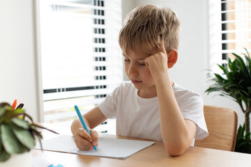 Cute boy doing school homework at home. Distance education. Online education.