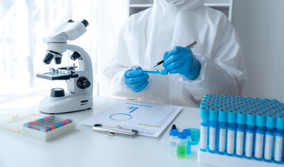 Doctor hand taking a blood sample tube from a rack with machines of analysis in the lab background, Technician holding blood tube test in the research laboratory.