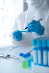 Doctor hand taking a blood sample tube from a rack with machines of analysis in the lab background,...