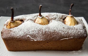 Whole Chocolate cake with poached pear on dark background