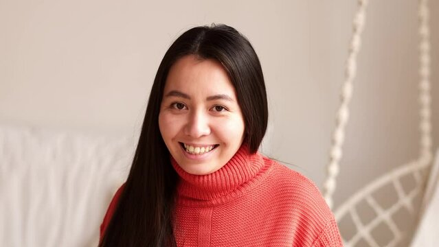 Portrait of young beautiful asian woman with long black hair smiling looking at camera indoors.
