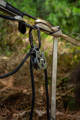 Obraz premium Vertical picture Details of Highline pulley, carabiner and ropes equipment with nature behind