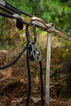 Vertical picture Details of Highline pulley, carabiner and ropes equipment with nature behind