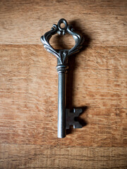 An old fashioned vintage key isolated on a wooden texture.