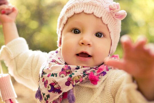 Closeup portrait of beautiful baby girl wearing stylish hat and cozy sweater. Outdoors spring, autumn photo. Seasonal clothes. Childhood.