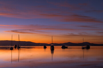 Beautiful sunrise waterscape with high cloud, reflections and boats