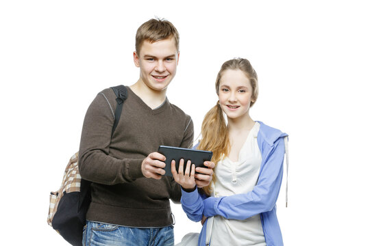 Beautiful teen age boy and girl in casual clothes holding mobile phones. School children texting using cellulars. Isolated on white background. Copy space.