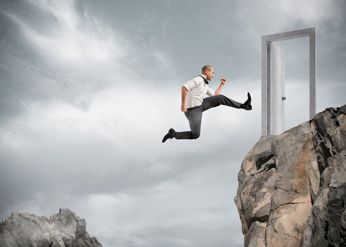 Businessman jumping over the mountains to reach a door. concept of ambition in business