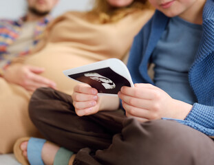 Parents inform child that they will soon have another baby. Preteen boy is looking of ultrasound pictures of new baby.