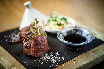 Close up of lamb chops with couscous and vegetables with a sauce of caramel and spices in a restaurant setting