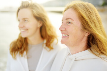 Redhead senior mother and her beautiful adult daughter are walking together and laughing