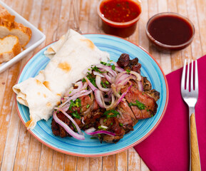 Spicy grilled pork meat skewers served with pickled onion and flatbread