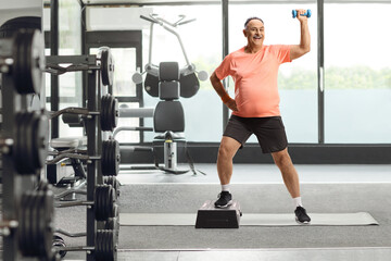Fototapeta na wymiar Mature man exercising step aerobic at gym