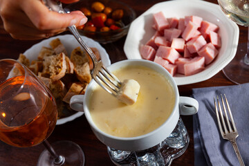 Cheese fondue with bread and snacks on a wooden table