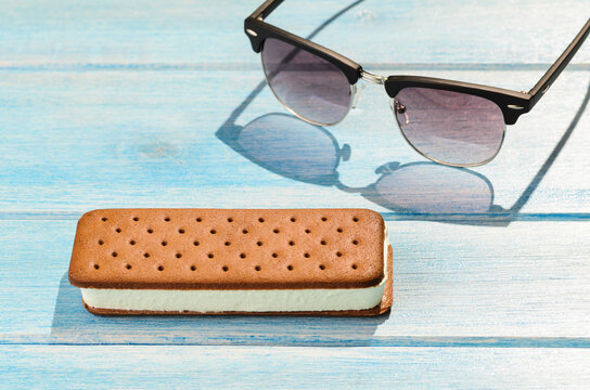 Ice cream sandwich with retro sunglasses on blue table outdoors