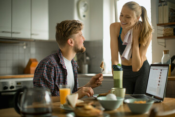 Young couple having breakfast together in the morning and using a laptop