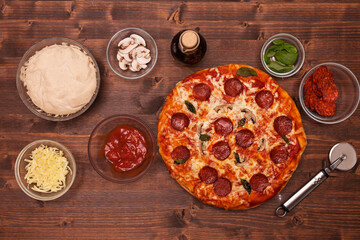Phases of making a pizza - the baked pizza ready to eat surrounded by the ingredients, top view