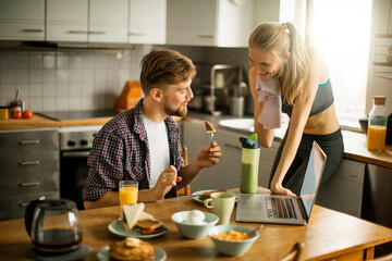 Young couple having breakfast together in the morning and using a laptop