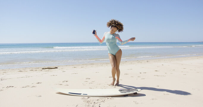 Female listening music in headphones and dancing on beach on sea background. Tarifa beach. Provincia Cadiz. Spain.