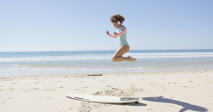 Female listening music in headphones and jumping on beach on sea background. Tarifa beach. Provincia Cadiz. Spain.