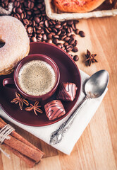 Cup fragrant hot coffee with bean chocolate sweet and loaf in vintage rustic style on wooden board for bracing morning breakfast
