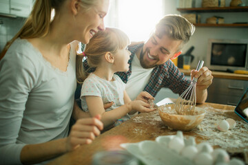 Young family baking a cake together in the kitchen