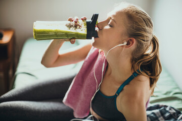 Young woman having a post workout shake at home after working out in the morning