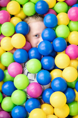 Fototapeta na wymiar Child in colored balls so that only the eyes peeping