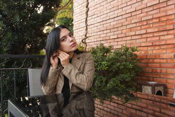 Beautiful young girl sitting waiting for breakfast, adjusting an earring in her ear.