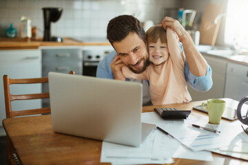 Young father and daughter using a laptop together in the morning