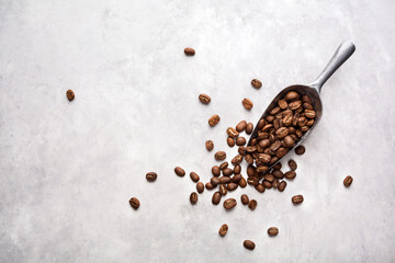 Fresh coffee beans in a metal scoop, light background with place for text