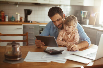 Single father using a digital tablet with his daughter in the morning while going over bills