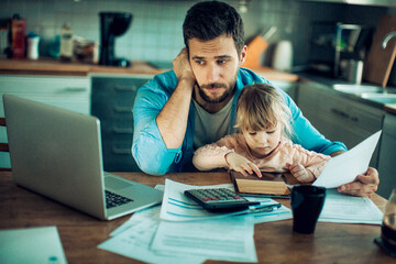 Single father going over the bills with his daughter in the lap