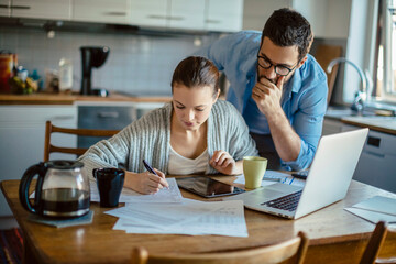 Young couple going over their bills at home in the kitchen
