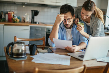 Young couple going over their bills at home in the kitchen