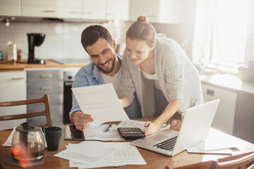 Young happy couple going over their bills at home