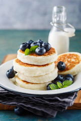 Cottage cheese pancakes with blueberries and milk, homemade traditional Ukrainian and Russian cuisine. Selective focus