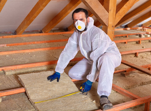 Man installing thermal insulation panels between wooden scaffolding