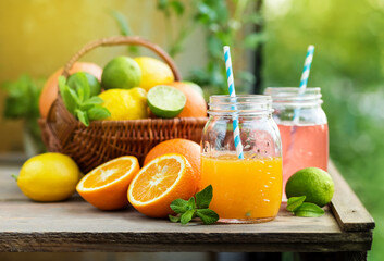 Mix of fresh citrus fruits in basket and juice in glass jars. Grapefruit and orange juice